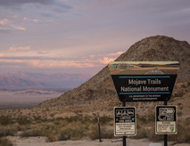 A desert landscape with a sign that reads Mojave Trails National Monument.