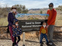 A family four in front of the sign for Sand to Snow National Monument.