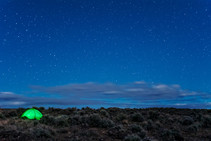 A night sky with an illuminated camp tent.