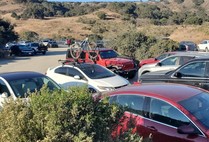 An overcrowded parking lot near hillsides.
