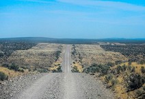 A gravel road through a bare, rolling landscape.
