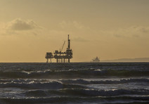 An oil rig in the ocean at sunset.