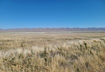 A large dry plain with mountains in the far background.