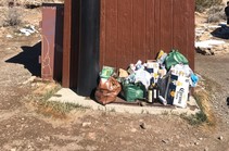 Trash piled next to a small brown building.