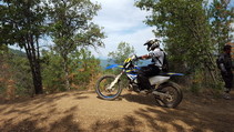 A dirtbike rider on a dirt trail in a forest.
