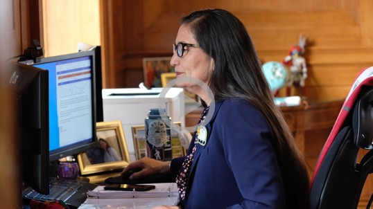 Secretary Haaland sits at her desk