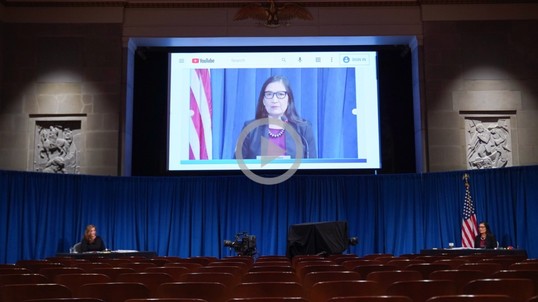 Secretary Haaland on a large screen tv presenting to an audience
