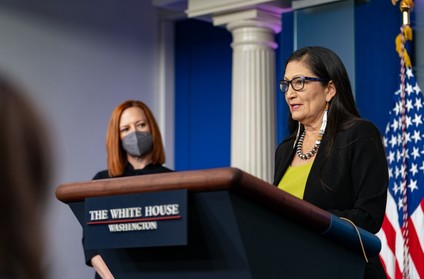 Secretary Haaland stands at a briefing podium and addresses reporters