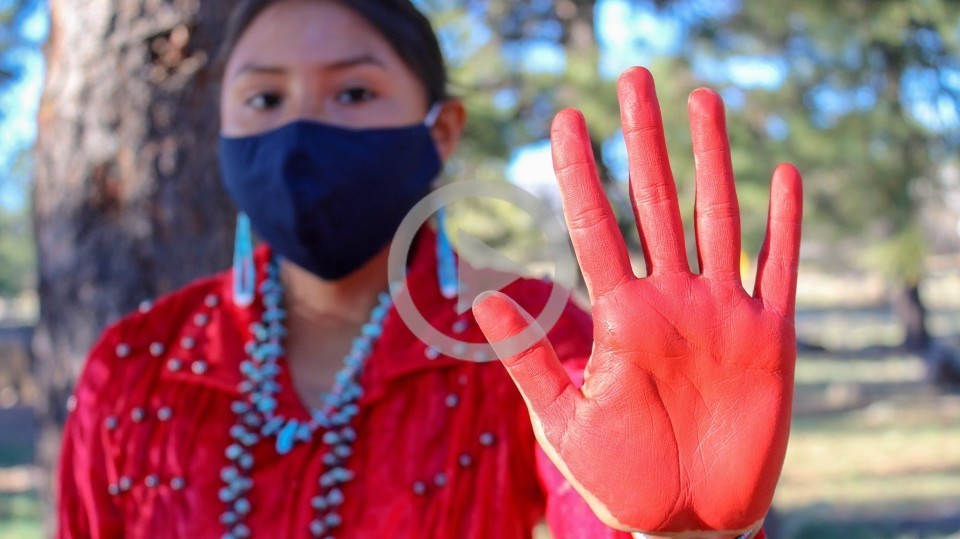 A person dressed in red holds out their red painted hand