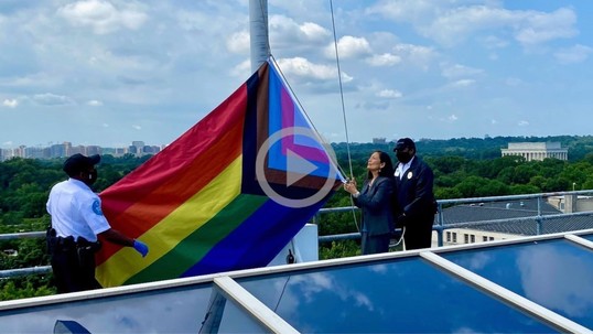Secretary Haaland helps two other people raise the Pride Month flag