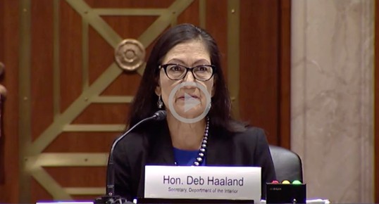 Secretary Haaland sits behind a desk as she testifies before the Senate