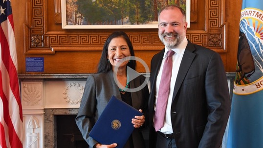 Secretary Haaland stands with a newly sworn in member of the Department