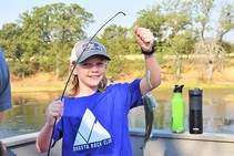 Child proudly holding their fishing line with a fish on it. 