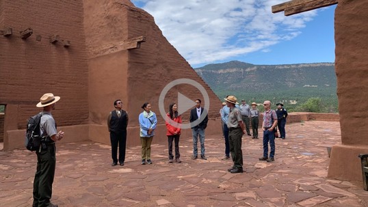 A group of people stand in an ancient set of pueblo ruins as a park ranger talks to them