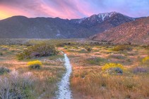 A trail through a mountain landscape during sunset. 
