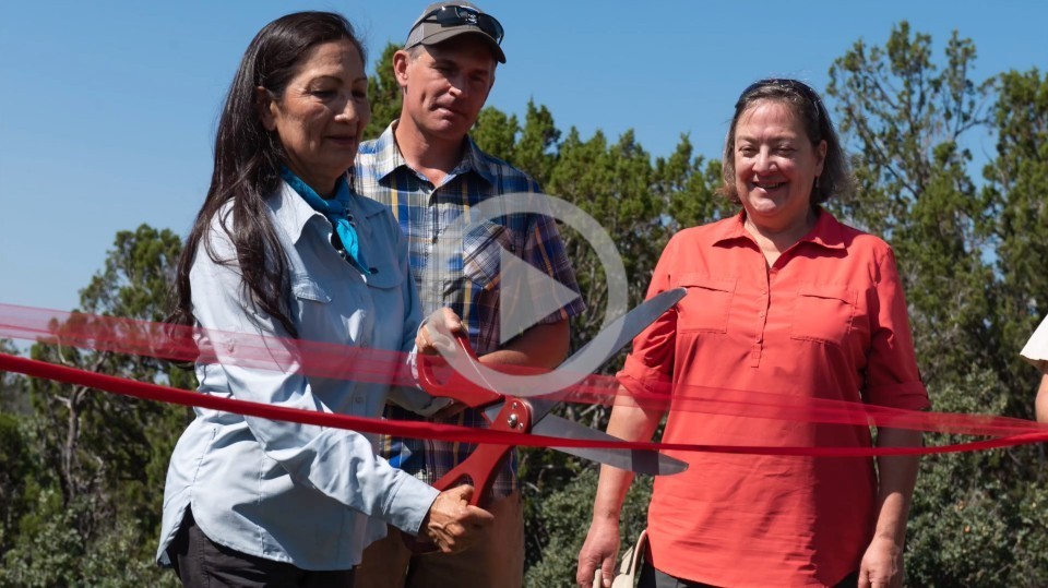 Secretary Haaland helps cut a red ribbon at an event