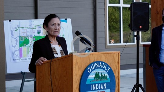 Secretary Haaland stands at a podium and addresses a group