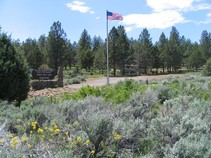 View of North Eagle Lake Campground in an open pine forest setting, BLM sign sits near American flag to welcome visitors