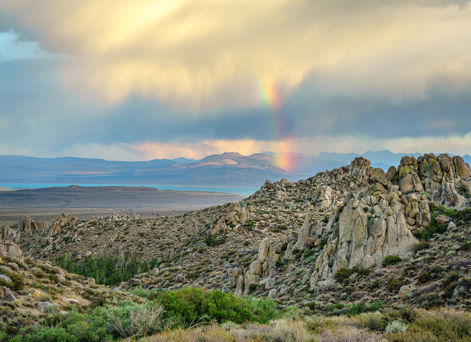 A rainbow over an outcrop of rocks and mountains.