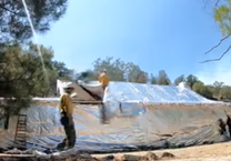 Fire fighters wrapping a building in an aluminum sheet.