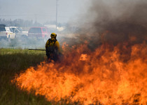 A firefighter next to a fire burning. 