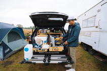 A man making a  meal in the back of his camping car.