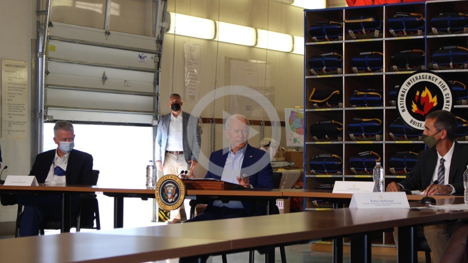 President Biden sits at a table and speaks to a group of people