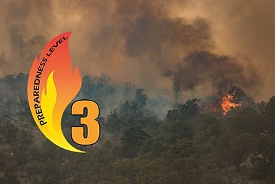 Preparedness Level 3 graphic over photo of dense trees with active fire and plumes of smoke.