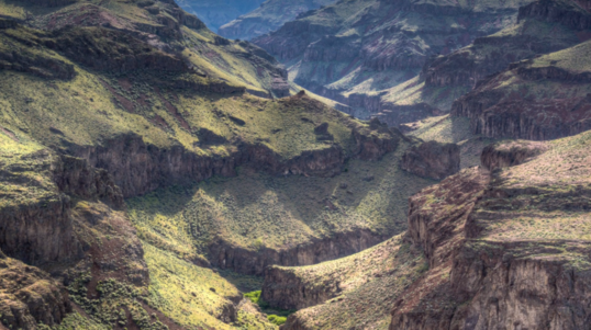 A steep green and grassy canyon cuts through Idaho