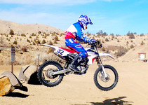 OHV Rice Canyon, a motorcross rider in mid air with desert landscape dotted with sparse shrubs
