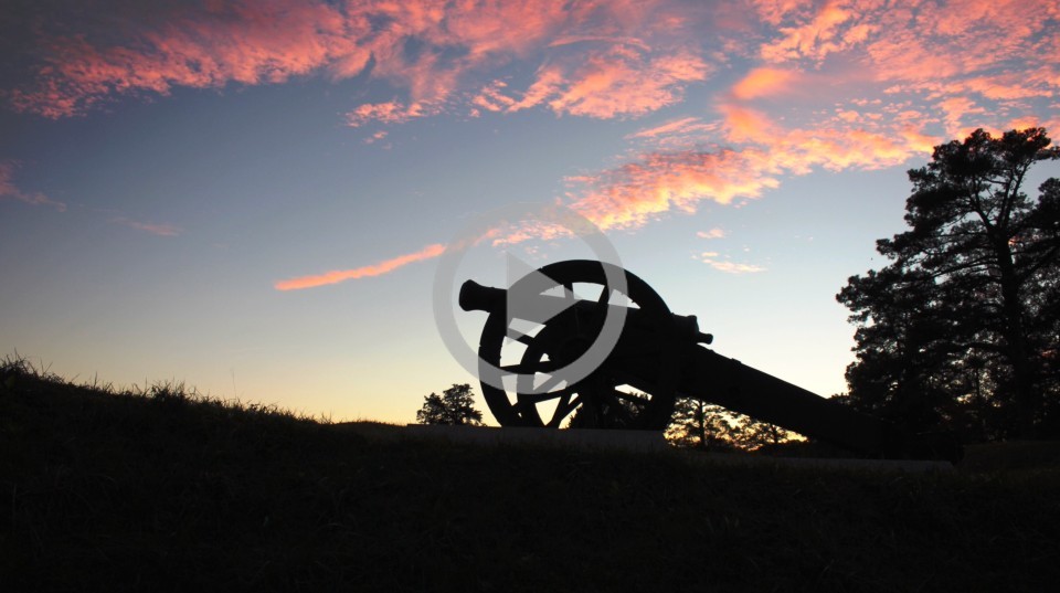 A canon from the Civil War era sits in a field at dusk
