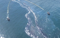 Two boats cleaning up an oil spill in the pacific ocean.