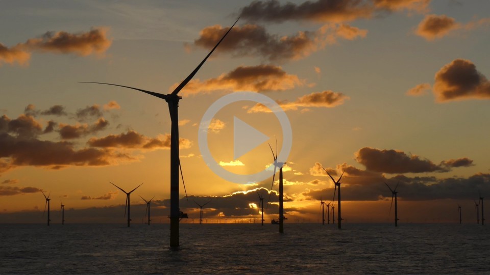 Wind turbines stand tall in a sunset sky