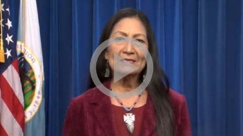 Secretary Haaland stands and delivers a speech for a video