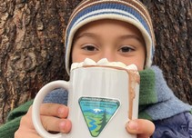 A kid with a mug of hot chocolate.