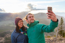 Two people taking a selfie on top of a mountain.