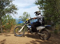 A dirt bike rider in the BLM Chappie-Shasta OHV area near Redding, Calif, tall conifers stand in the background. (BLM)