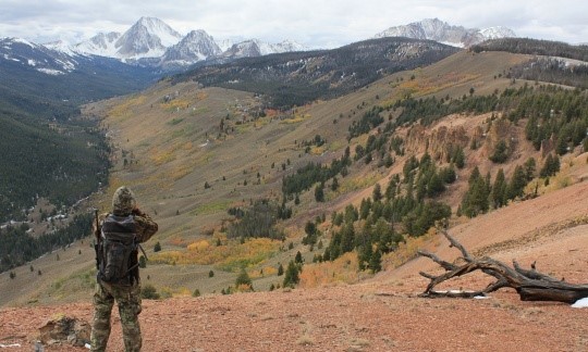 Person in camo stands looking out toward mountains. Photo by BLM.