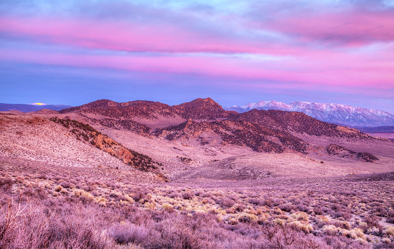 Landscape view of Granite Mountain Wilderness washed in pink hues with snow capped mountains in the distance.