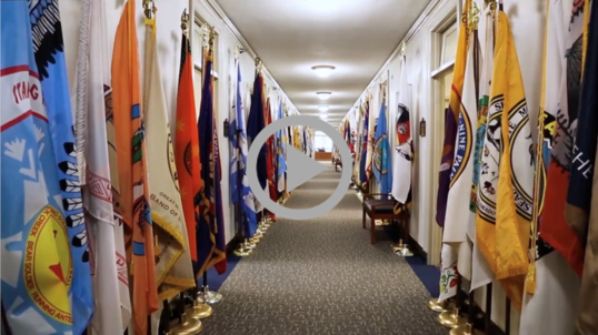 Two rows of Tribal Flags proceed down a hallway at the Bureau of Indian Affairs