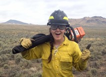 A firefighter holding a chainsaw on her shoulder.