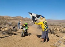 A child riding a motorcycle across a finish line.