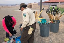 A person in a BLM uniform picking up trash.