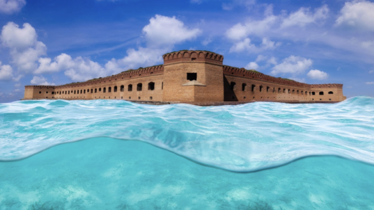 an old brick fort rises above the bright blue green waters of the Gulf of Mexico