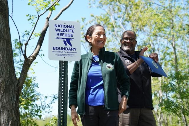 Secretary Haaland stands next to a sign that reads: "National Wildlife Refuge Boundary." Photo by DOI.
