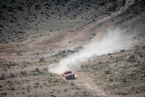 An off-road vehicle driving down a rocky dirt road on a mountain.