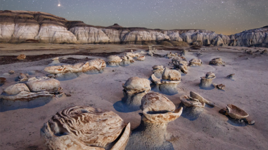 a bizarre landscape of strange rock formations under a starry desert sky
