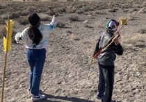 Children throwing arrows in a desert.