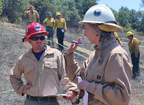 Three people in uniforms and hard hats talking.