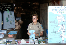 A woman in uniform behind a booth table handing our flyers.